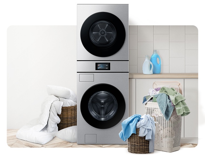 Bespoke AI 원바디가 중앙에 나와있고 좌측 뒷편 라탄 바구니에 의류가 가득 쌓여있고 앞쪽에 이불이 나와있습니다. 우측 파란색 플라스틱 바구니에도 수건 등 각종 옷감이 가득 쌓여있는 연출된 이미지입니다.