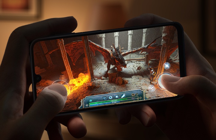 조명이 어두운 공간에서 두 손으로 갤럭시 버디4를 잡고, 그래픽 중심의 비디오 게임을 플레이하고 있습니다.