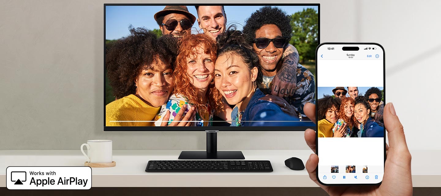 아이폰을 쥐고 있는 손과 모니터를 보여줍니다. 아이폰에 있는 사진이 모니터에 그대로 출력 됩니다.