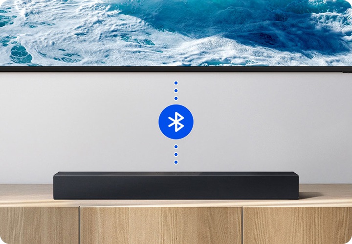 거실 벽에 TV가 설치되어 있습니다. TV와 사운드바가 연결되어 있고 블루투스 아이콘이 보입니다.