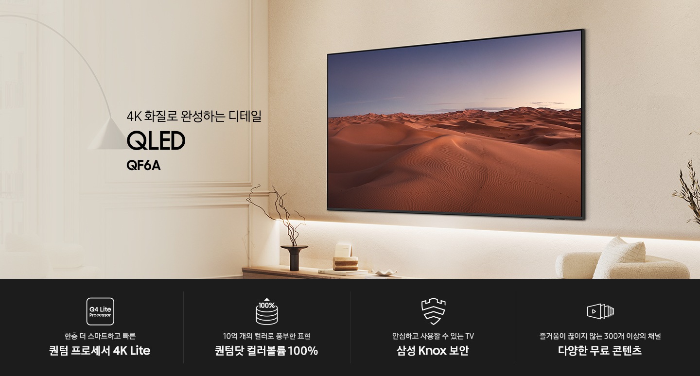 벽에 TV가 설치되어 있습니다. 화면에는 사막이 보입니다. 4K 화질로 완성하는 디테일 QLED QF6A KV입니다. 하단에는 한층 더 스마트하고 빠른 퀀텀 프로세서 4K Lite, 10억 개의 컬러로 풍부한 표현 퀀텀닷 컬러볼륨 100%, 안심하고 사용할 수 있는 TV 삼성 Knox 보안, 즐거움이 끊이지 않는 300개 이상의 채널 다양한 무료 콘텐츠 문구와 아이콘이 있습니다.