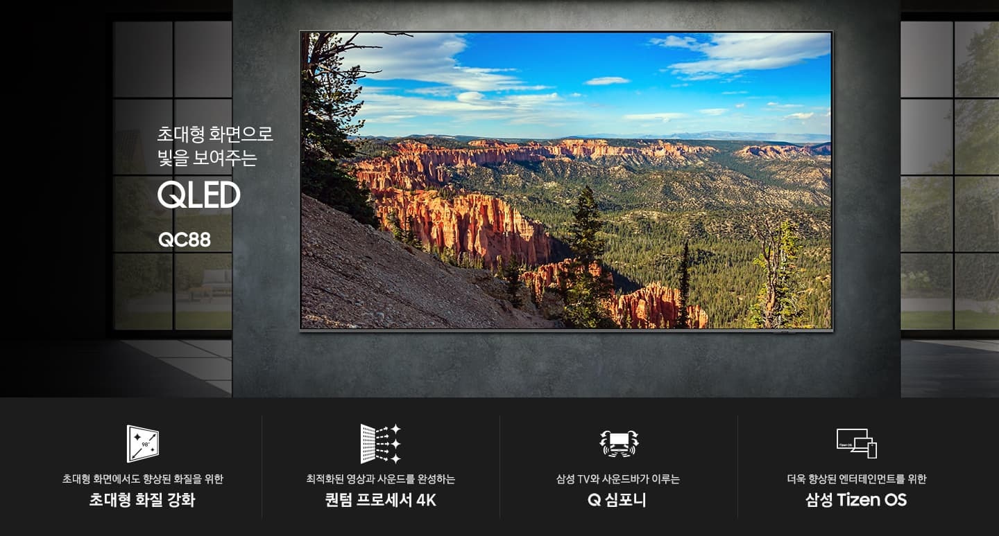 거실 벽면에 초대형 TV가 설치되어 있습니다. 초대형 화면으로 빛을 보여주는 QLED QC88 KV입니다. 하단에는 초대형 화면에서도 향상된 화질을 위한 초대형 화질 강화, 최적화된 영상과 사운드를 완성하는 퀀텀 프로세서 4K, 삼성 TV와 사운드바가 이루는 Q 심포니, 더욱 향상된 엔터테인먼트를 위한 삼성 Tizen OS 문구와 아이콘이 있습니다.