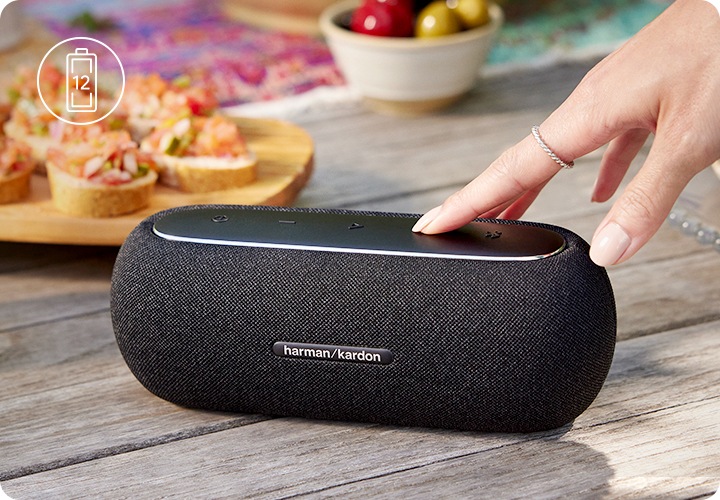 야외 테이블 위에 스피커가 놓여 있습니다. 테이블 위에는 각종 음식과 음료가 놓여있습니다.