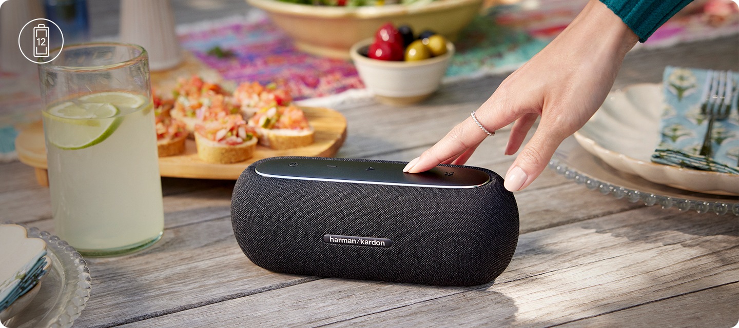 야외 테이블 위에 스피커가 놓여 있습니다. 테이블 위에는 각종 음식과 음료가 놓여있습니다.