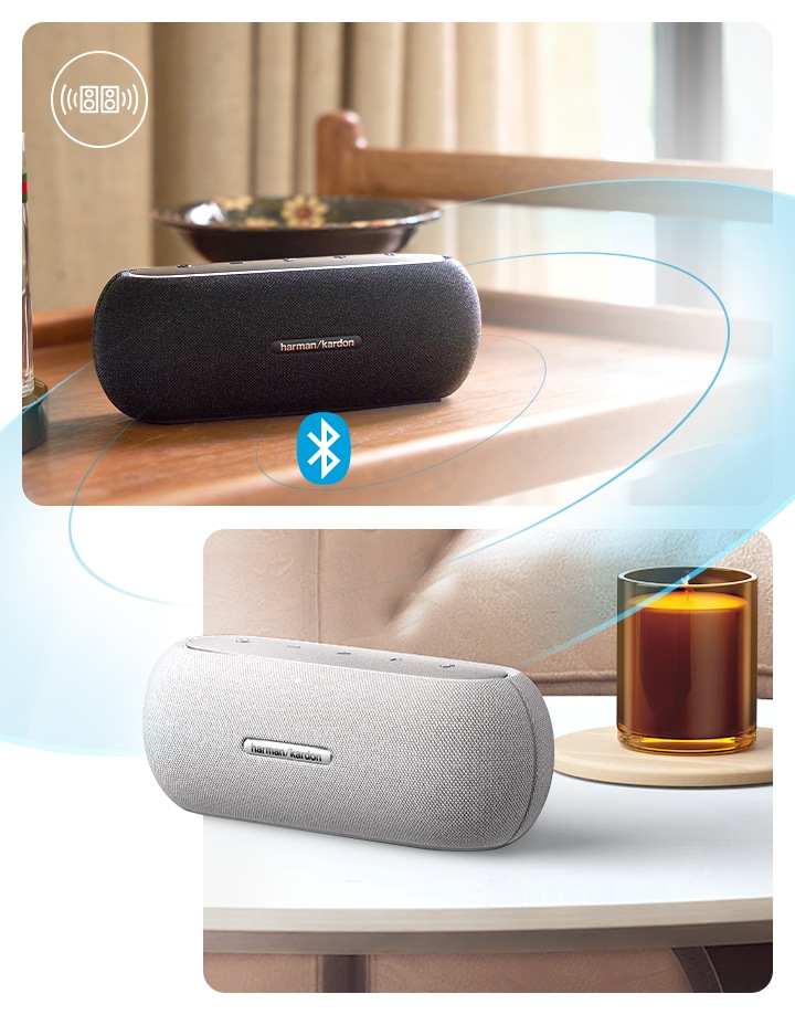 스피커 두 대가 블루투스 페이링으로 연결되어 있습니다. 왼쪽에는 블랙 색상의 스피커가 이동식 트레이 위에 놓여 있습니다. 스피커 왼쪽에는 유리잔들이 있으며, 스피커 뒤에는 접시가 놓여 있습니다. 오른쪽에는 테이블 위에 스피커가 놓여 있습니다. 스피커 뒤로는 향초와 소파가 보입니다.