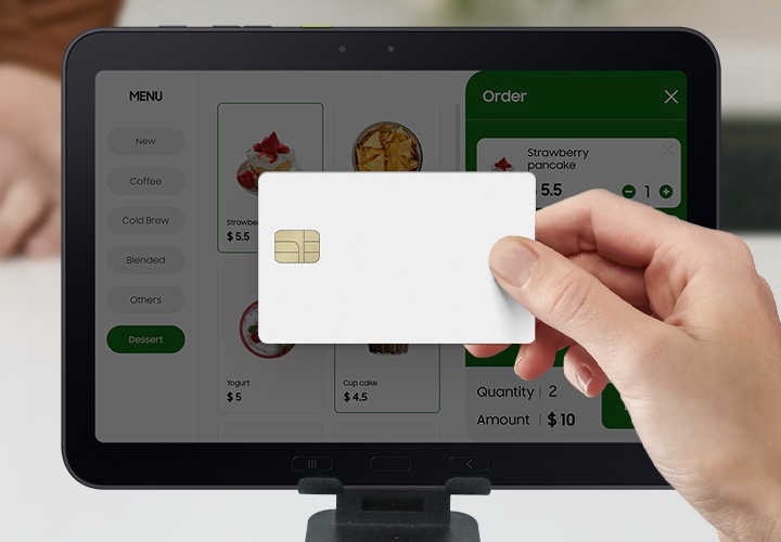 갤럭시 탭 액티브5 프로 화면 근처에서 신용카드를 들고 식당에서 결제를 하고 있는 모습입니다. 갤럭시 탭 액티브5 프로는 메뉴 표시, 주문 접수, 결제 처리에 사용될 수 있음을 알려줍니다.