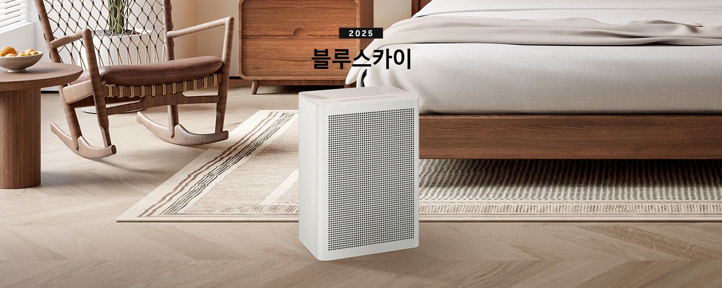 우드와 베이지 톤의 침실이 배경으로 보이고 있습니다. 이미지 중간 부분에는 블루스카이 3100 제품이 서있고 제품 이미지 상단 부분에는 2025 블루스카이 텍스트가 적혀 있습니다. 제품 이미지 왼쪽 부분에는 우드로 제작된 동그란 테이블과 흔들의자가 배치되어 있고 제품 이미지 오른쪽 부분에는 침대가 보이고 있습니다.