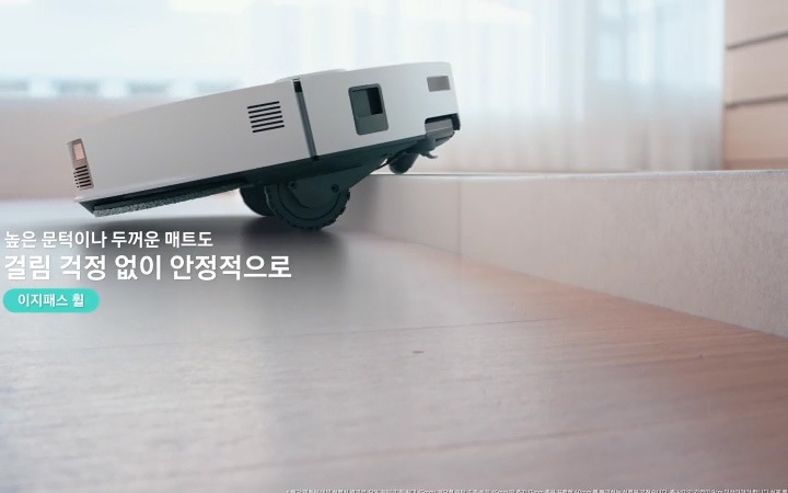 Bespoke AI 스팀 울트라가 문턱에 접근 후 전방을 스캔하여 문턱 높이가 45mm 임을 감지하고 스팀의 내부가 투영되며 5개의 바퀴가 파란색 빛으로 강조되고 있는 모습을 알려주며 제품 왼쪽 부분에는 5개 바퀴를 이용해, 계단형 60mm 단일 문턱도 최대 45mm 높이도 거뜬히 넘는 이지패스 휠 텍스트로 현재 영상 부분을 설명해 주고 있습니다. 추가로 영상의 하단 부분에는 단일 문턱 기준 최대 45mm/ 계단형 단차 기준 하부 45mm 및 추가 15mm 층을 포함한 60mm를 통과할 수 있으며, 각 층 사이의 간격이 90mm 이상이어야 하는 부분을 그림으로 그려 설명하고 있습니다. 이어서 전방 휠 하강으로 몸체를 들어 올리고 이지패스 휠 텍스트가 왼쪽에 쓰여 있으며, Bespoke AI 스팀 울트라의 바닥 부분을 보여주며 5개 바퀴 중 제일 앞부분에 있는 전방 휠이 하강하면서 몸체를 들어 올리는 모습을 알려주고 있습니다. 다음 장면은 메인&사이드 휠 하강으로 문턱 위 이동 및 충격 방지 이지패스 휠 텍스트가 왼쪽에 쓰여 있고 메인 휠과 사이드 휠이 하강한 후 Bespoke AI 스팀 울트라가 자동으로 문턱/ 두꺼운 매트를 넘는 모습을 설명해주는 영상입니다. 계속 이어서 높은 문턱이나 두꺼운 매트도 걸림 걱정 없이 안정적으로 라는 텍스트가 왼쪽에 쓰여 있으며 Bespoke AI 스팀 울트라가 높은 곳을  자동으로 높이가 조절되며 본체를 들어올려 두꺼운 매트를 올라 그 위를 돌아다니는 Bespoke AI 스팀 울트라의 상단 모습과 집 안 곳곳을 어디든 자유롭게 텍스트가 나타나며 영상이 마무리 됩니다.