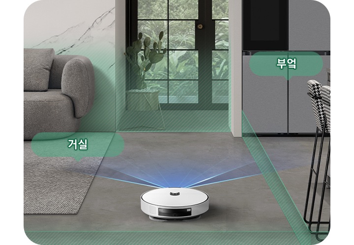 채도가 낮은 색상의 거실과 부엌을 배경으로 Bespoke AI 스팀 울트라의 뒷 모습이 이미지 중간 하단 부분에 있으며, 이미지 왼쪽 부분에는 회색의 카펫트가 카펫트 위에는 더 진한 회색의 소파와 어두운 색상의 우드 테이블이 놓여 있고 소파와 카펫트가 만나는 부분에는 반투명한 초록색 말풍선에 거실이라는 텍스트가 쓰여 있습니다. 이미지 오른쪽 부분에는 체크무늬의 높은 의자 2개가 회색 대리석의 주방 테이블 옆에 배치되어 있고 냉장고가 테이블 왼쪽 부분에 놓여 있으며 냉장고 앞부분에는 반투명한 초록색 말풍선에 부엌이라는 텍스트가 쓰여 있습니다. Bespoke AI 스팀 울트라가 집 안을 스캔해 거실과 주방을 초록색 빗금이 그려진 반투명 박스로 구분하며 각 공간을 인식하는 모습을 보여주고 있습니다.