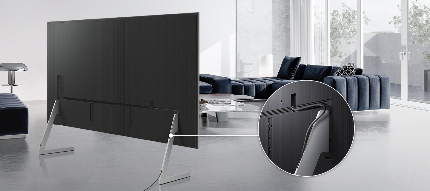 TV에 플로어 스탠드가 장착되어 있으며, 플로어 스탠드가 확대되어 보입니다. 확대된 이미지에는 케이블이 플로어 스탠드 다리로 들어가 선이 정돈된 걸 보여줍니다.