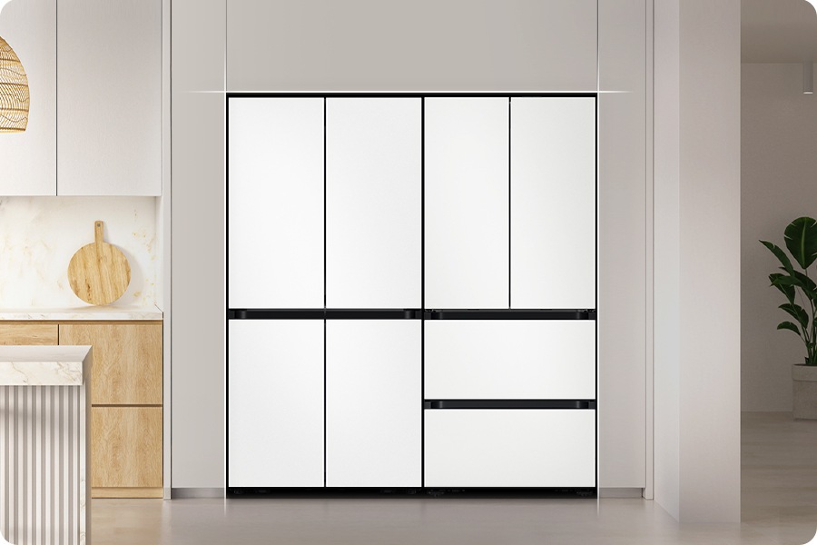 [화이트톤 주방 냉장고장에 냉장고 4도어와 김치냉장고 4도어 키친핏 모델이 딱 맞게 설치되어 있는 연출된 이미지 입니다. 냉장고장 우측으로는 벽과 화분이 보이고, 좌측에는 우드톤 하부장과 아일랜드 식탁이 나와있습니다.]