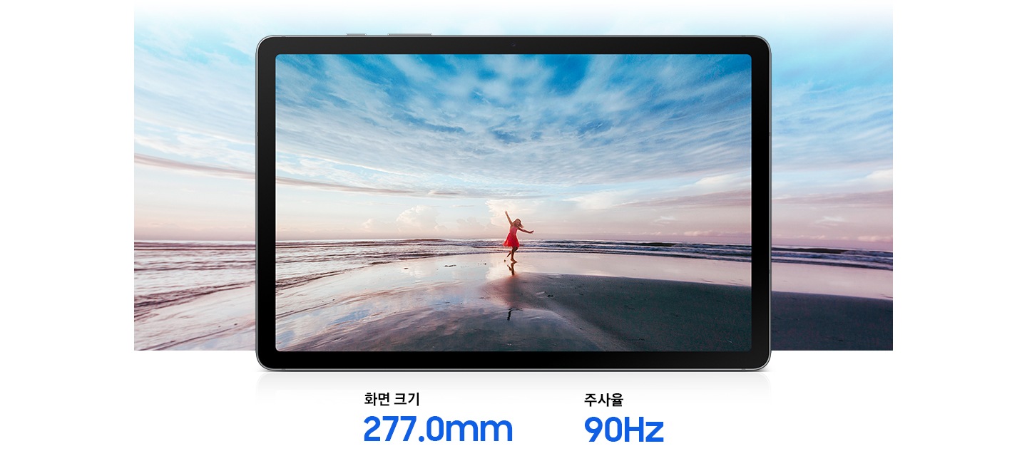 갤럭시 탭 S10 라이트가 가로로 놓여 있습니다. 화면에는 붉은 드레스를 입은 여성이 해변에서 푸른 하늘과 수평선을 향해 팔을 뻗고 있는 생동감 넘치는 이미지가 있습니다. 화면 밖을 넘어 확장된 이미지는 277.0mm의 대화면 디스플레이와 몰입감 넘치는 시청 경험을 강조합니다. 하단에는 화면 크기 277.0mm, 주사율 90Hz라고 적혀 있습니다.