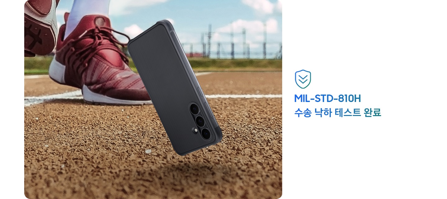 러기드 케이스가 장착된 갤럭시 S25 FE가 야외 트랙 바닥에 떨어지기 직전의 모습으로 2.5cm 정도 공중에 떠 있어, 낙하 사고가 발생했음을 알려줍니다. 떨어지는 스마트폰 뒤로 러닝화를 신은 사람의 발이 있습니다. 이미지 우측에는 '미국 국방부 군사 표준 규격 MIL-STD-810H에 따른 테스트'라는 표시가 있습니다.