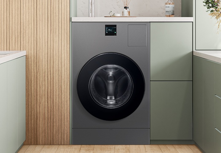 다용도실에 BESPOKE AI 콤보 제품이 가운데 있습니다. 제품 옆에서 수납장 있고 위에는 물건들이 놓여져있습니다. 좌측에는 세면대 있고 우측에는 수납장 위에 꽃병이보입니다