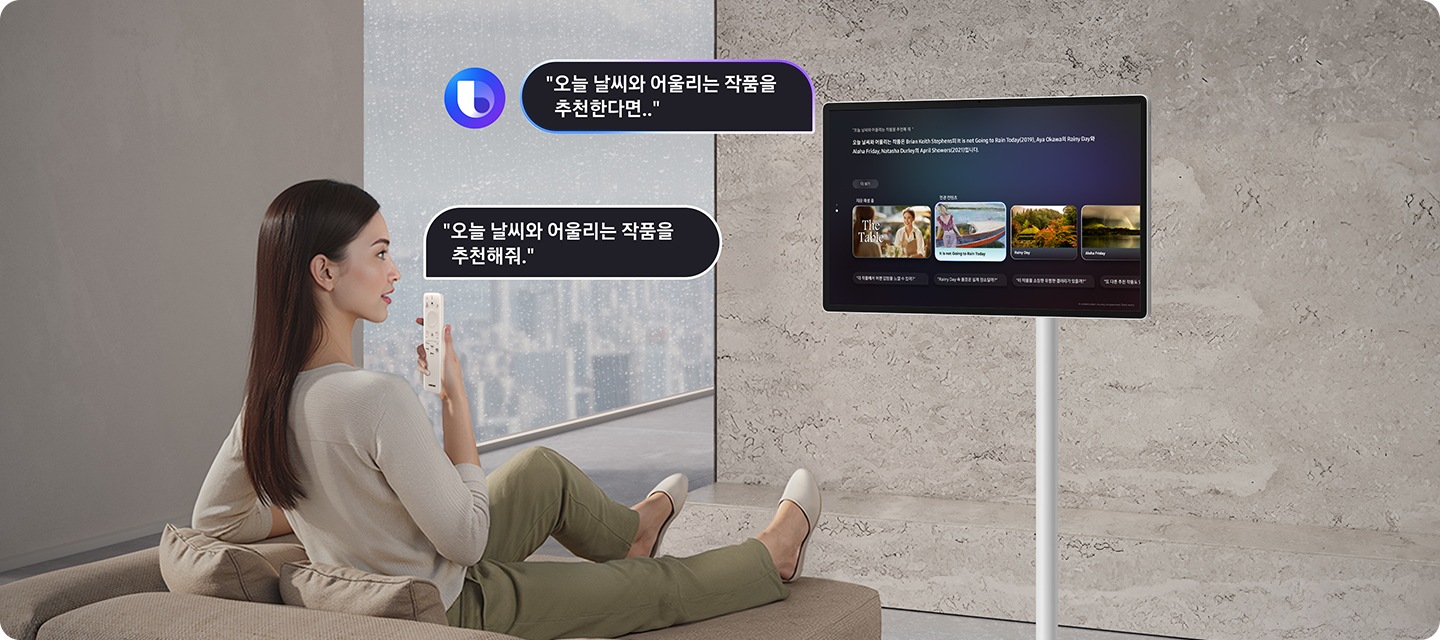 여성이 소파에 앉아서 리모컨으로 The Movingstyle에 오늘 날씨와 어울리는 예술 작품을 추천 요청하고 있으며, The Movingstyle은 오늘 날씨와 어울리는 예술 작품을 추천하고 있습니다.