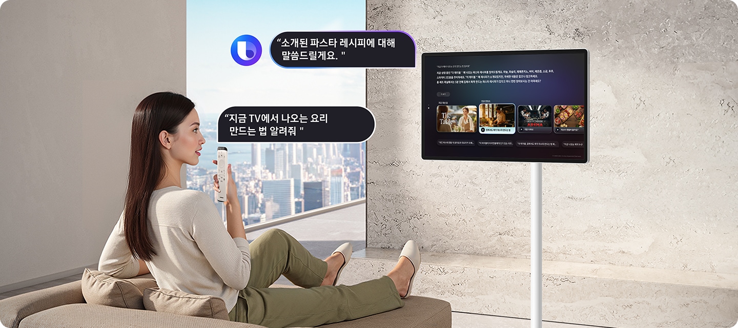 여성이 소파에 앉아서 리모컨으로 The Movingstyle에 TV에 나오는 요리 만드는 법을 알려달라고 요청하고 있으며, The Movingstyle은 여성이 말한 파스타 레시피를 알려주고 있습니다.