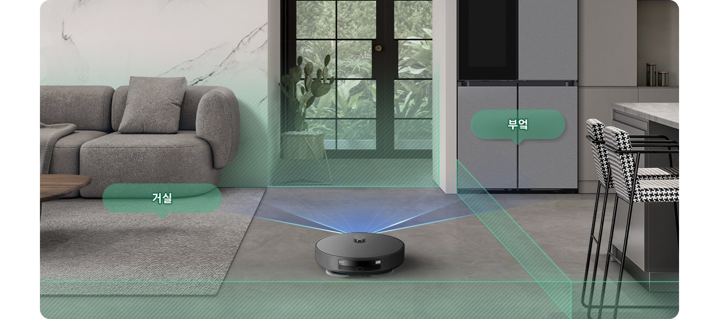 채도가 낮은 색상의 거실과 부엌을 배경으로 Bespoke AI 스팀 울트라의 뒷 모습이 이미지 중간 하단 부분에 있으며, 이미지 왼쪽 부분에는 회색의 카펫트가 카펫트 위에는 더 진한 회색의 소파와 어두운 색상의 우드 테이블이 놓여 있고 소파와 카펫트가 만나는 부분에는 반투명한 초록색 말풍선에 거실이라는 텍스트가 쓰여 있습니다. 이미지 오른쪽 부분에는 체크무늬의 높은 의자 2개가 회색 대리석의 주방 테이블 옆에 배치되어 있고 냉장고가 테이블 왼쪽 부분에 놓여 있으며 냉장고 앞부분에는 반투명한 초록색 말풍선에 부엌이라는 텍스트가 쓰여 있습니다. Bespoke AI 스팀 울트라가 집 안을 스캔해 거실과 주방을 초록색 빗금이 그려진 반투명 박스로 구분하며 각 공간을 인식하는 모습을 보여주고 있습니다.