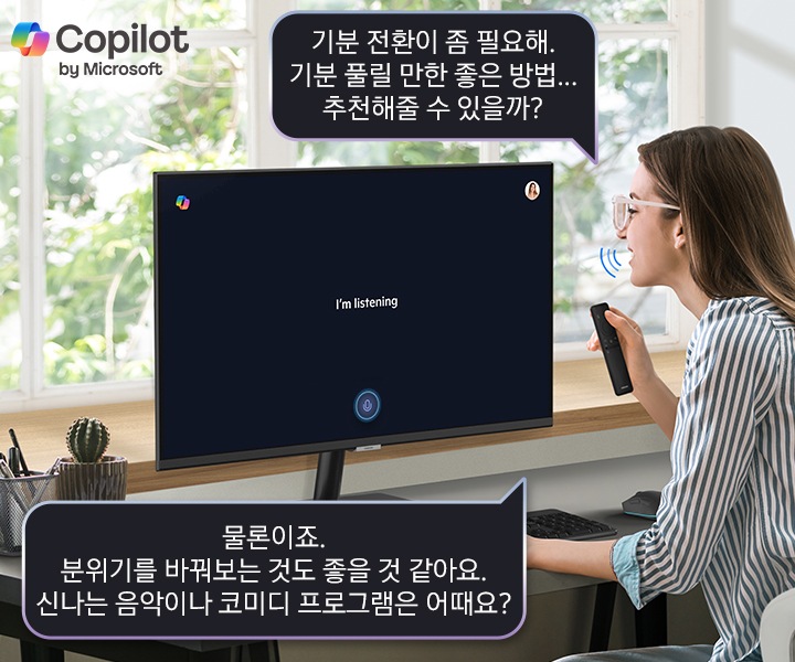 스마트 모니터 앞에 솔라셀 리모트를 손에 쥐고 있는 사람이 앉아 [기분 전환이 좀 필요해. 기분 풀릴 만한 좋은 방법... 추천해줄 수 있을까?] 라고 음성 명령을 합니다. 스마트 모니터 화면에는 I’m listing 이라고 쓰여 있고 아래 말풍선에 [물론이죠. 분위기를 바꿔보는 것도 좋을 것 같아요. 신나는 음악이나 코미디 프로그램은 어때요?] 라는 답이 보입니다.