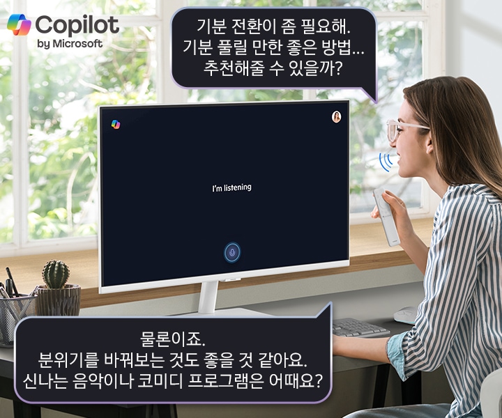 스마트 모니터 앞에 솔라셀 리모트를 손에 쥐고 있는 사람이 앉아 [기분 전환이 좀 필요해. 기분 풀릴 만한 좋은 방법... 추천해줄 수 있을까?] 라고 음성 명령을 합니다. 스마트 모니터 화면에는 I’m listing 이라고 쓰여 있고 아래 말풍선에 [물론이죠. 분위기를 바꿔보는 것도 좋을 것 같아요. 신나는 음악이나 코미디 프로그램은 어때요?] 라는 답이 보입니다.