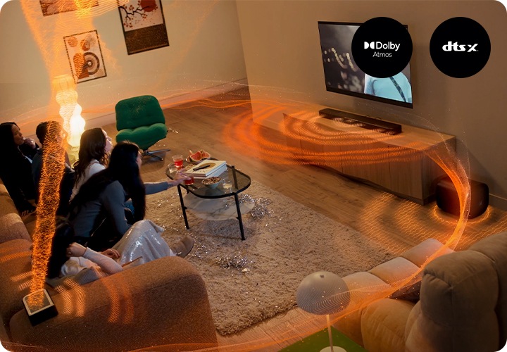 사람들이 소파에 앉아서 TV를 보고 있습니다. TV 아래에는 장식장이 놓여 있으며, 장식장 위에는 사운드바가 놓여 있고 장식장 오른쪽에는 우퍼가 놓여 있습니다. 소파 양 끝에 놓인 리어스피커와 사운드바, 우퍼에서 음향효과가 나오고 있습니다.