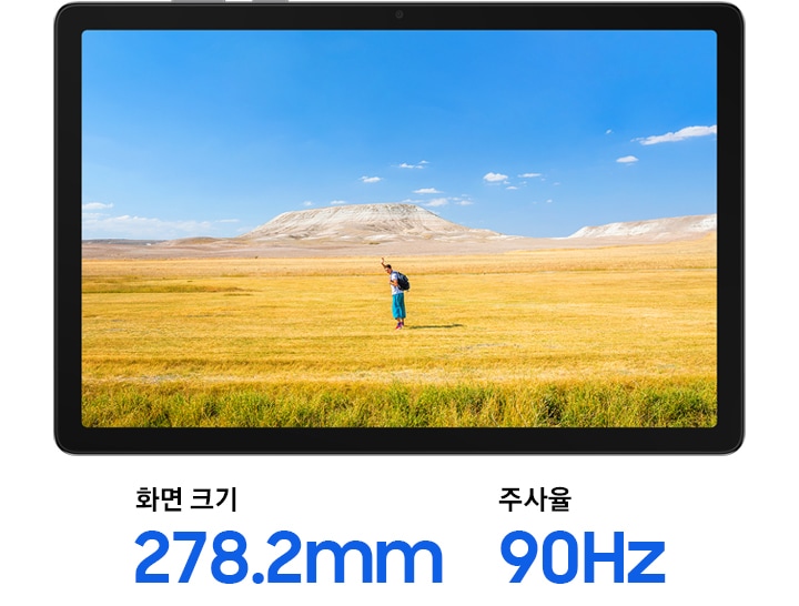 갤럭시 탭 A11+가 가로로 놓여 있으며 화면에는 지평선 위에서 손을 흔드는 남성의 선명한 이미지가 표시됩니다. 노란 잔디가 깔린 평원 위로 푸른 하늘이 펼쳐져 있습니다. 기기 아래에는 화면 크기 279.4mm, 주사율 90Hz라는 문구가 적혀 있습니다.