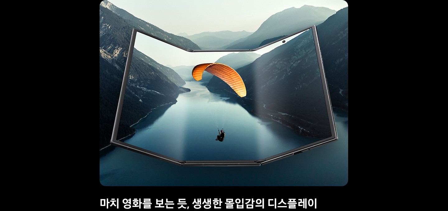 갤럭시 Z 트라이폴드가 거의 펼쳐진 상태로 넓은 메인 디스플레이를 드러냅니다. 화면에는 풍경 이미지가 표시되며 이미지는 기기 밖으로 이어져 영화 같은 장면을 강조합니다.