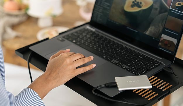 배경에 우드 테이블이 있으며, 노트북 받침대에서 노트북에 제품을 연결해 사용하고 있는 이미지입니다.