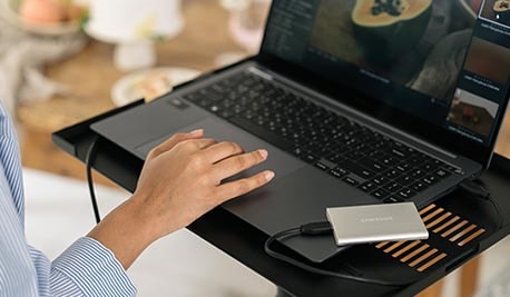 배경에 우드 테이블이 있으며, 노트북 받침대에서 노트북에 제품을 연결해 사용하고 있는 이미지입니다.