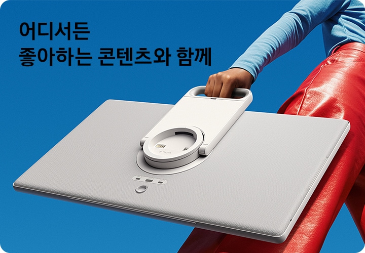 여성이 스탠드에서 분리된 The Movingstyle을 들고 이동하고 있습니다. 좌측 상단에는 '어디서든 좋아하는 콘텐츠와 함께' 문구가 기재되어 있습니다.