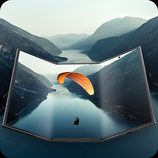 갤럭시 Z 트라이폴드가 거의 펼쳐진 상태로 넓은 메인 디스플레이를 드러냅니다. 화면에는 풍경 이미지가 표시되며 이미지는 기기 밖으로 이어져 영화 같은 장면을 강조합니다.