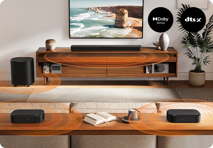 거실 벽에는 TV가 설치되어 있으며, 그 아래에는 스피커와 장식품이 놓인 장식장이 보입니다. 장식장 왼쪽에는 서브우퍼가 놓여 있으며, 오른쪽에는 화분이 놓여 잇습니다. 장식장 앞에는 소파가 놓여 있으며, 그 뒤에는 리어스피커가 놓인 장식장이 있습니다. 사운드바와 서브우퍼, 리어스피커에서는 음향효과가 나옵니다.