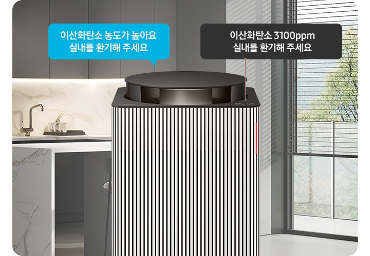 그레이 톤의 주방 전경을 배경으로 오른쪽에는 아일랜드 식탁 의자 2개와 블라인드가 내려진 커다란 창문이 놓여 있습니다. 이미지 가운데에 Infinite AI 공기청정기 상단부가 확대되어 보입니다. 공기청정기 상단에는 알림 창 부분이 이산화탄소 3100ppm 실내를 환기해 주세요. 가 확대되어 놓여 있고 공기청정기 오른쪽으로 음성 안내를 표시하는 파란색 말풍선 안에 이산화탄소 농도가 높아요 실내를 환기해 주세요.라는 문구가 적혀 있습니다.