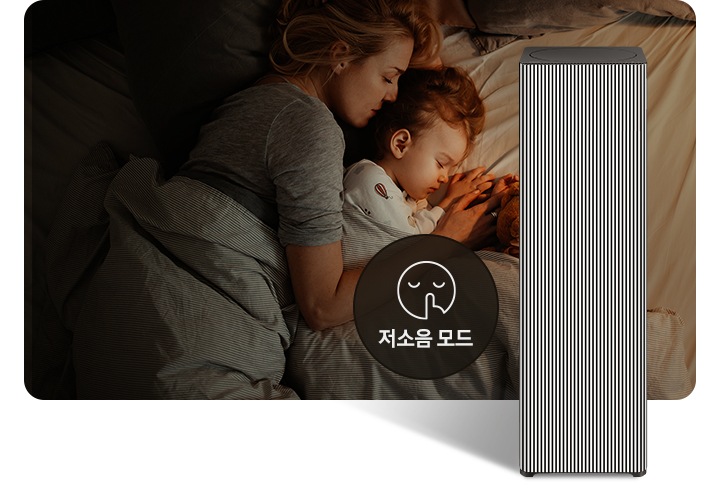 베이지 톤의 침구가 깔린 침대에 누워 회색 이불을 덮고 잠들어 있는 엄마와 아기의 옆모습이 있습니다. 오른쪽 하단에는 Infinite AI 공기청정기가 정면을 바라보고 서 있습니다. 공기청정기 왼쪽에는 검은색 원 안에 입을 가리는 모습을 한 사람 얼굴 아이콘이 있고 하단에는 저소음 모드라는 문구가 적혀 있습니다.