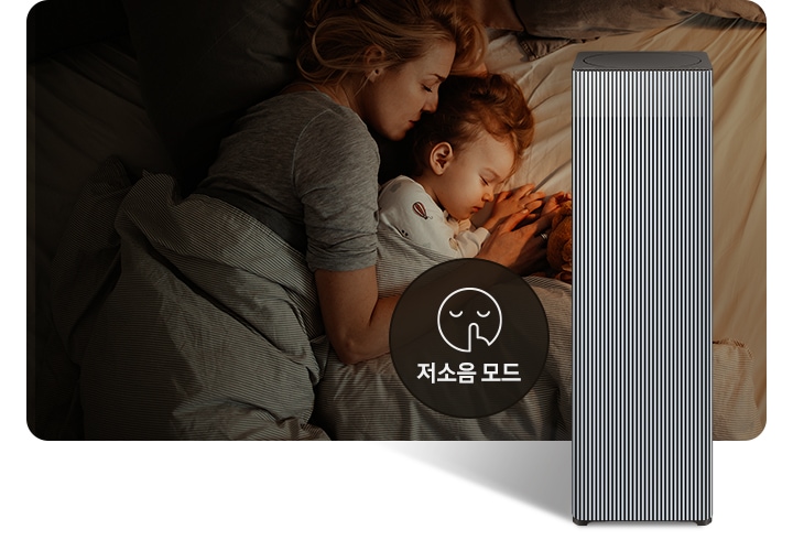 베이지 톤의 침구가 깔린 침대에 누워 회색 이불을 덮고 잠들어 있는 엄마와 아기의 옆모습이 있습니다. 오른쪽 하단에는 Infinite AI 공기청정기가 정면을 바라보고 서 있습니다. 공기청정기 왼쪽에는 검은색 원 안에 입을 가리는 모습을 한 사람 얼굴 아이콘이 있고 하단에는 저소음 모드라는 문구가 적혀 있습니다.