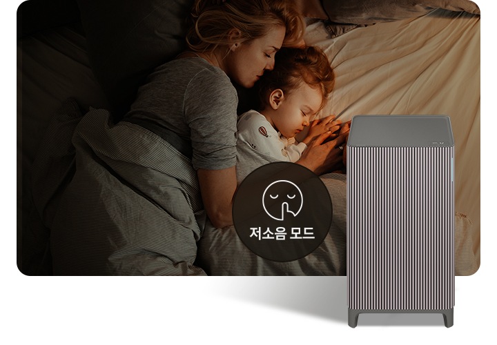 베이지 톤의 침구가 깔린 침대에 누워 회색 이불을 덮고 잠들어 있는 엄마와 아기의 옆모습이 있습니다. 오른쪽 하단에는 Infinite AI 공기청정기가 정면을 바라보고 서 있습니다. 공기청정기 왼쪽에는 검은색 원 안에 입을 가리는 모습을 한 사람 얼굴 아이콘이 있고 하단에는 저소음 모드라는 문구가 적혀 있습니다.