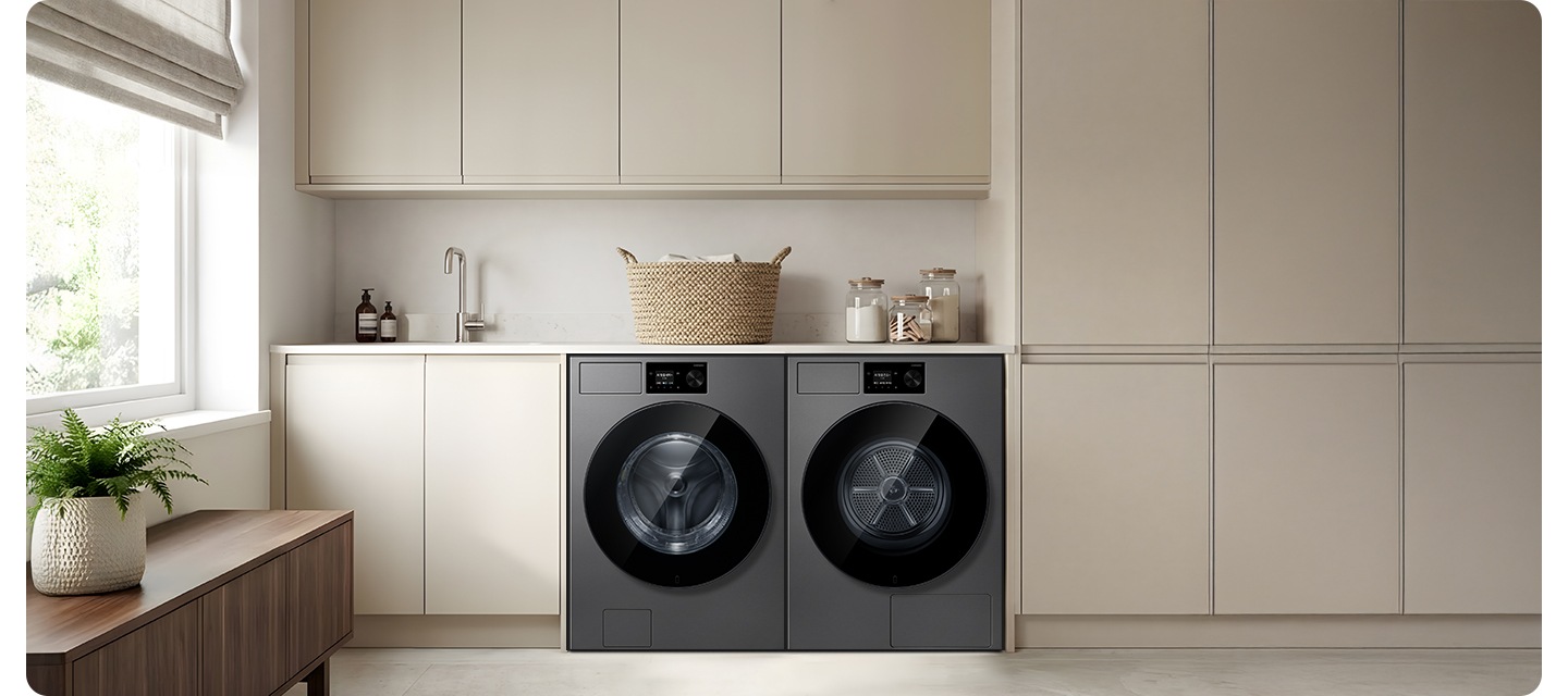 그레이톤 하부장에 세탁기와 건조기가 병렬로 설치되어 있습니다. 하부장 위에는 각종 오브제가 작은 싱크대가 설치되어 있는 연출된 이미지입니다.