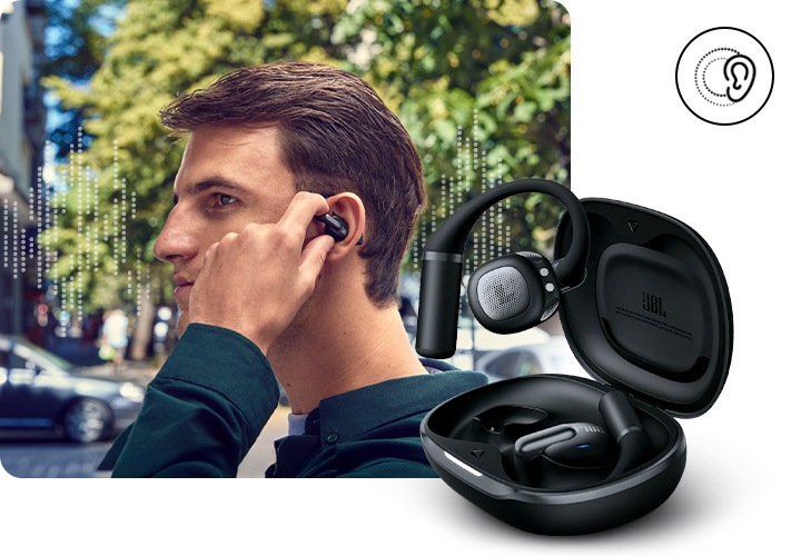 블랙 색상의 이어폰을 착용한 남성이 이어폰을 만지고 있습니다. 남성 뒤로는 음향효과와 자동차, 가로수들이 있습니다. 이미지 왼쪽 하단으로는 블랙 색상의 뚜껑이 열린 케이스에서 왼쪽 이어폰이 밖으로 나와 있습니다.