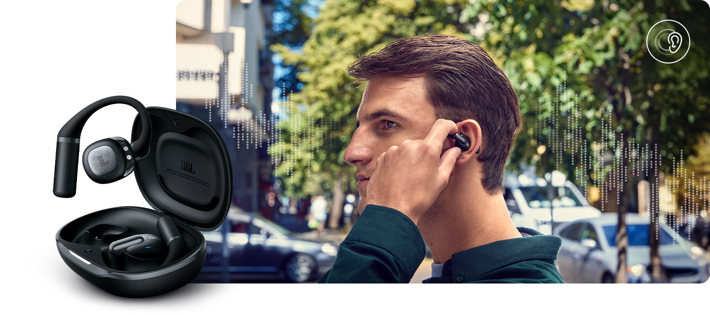 블랙 색상의 이어폰을 착용한 남성이 이어폰을 만지고 있습니다. 남성 뒤로는 음향효과와 자동차, 가로수들이 있습니다. 이미지 왼쪽 하단으로는 블랙 색상의 뚜껑이 열린 케이스에서 왼쪽 이어폰이 밖으로 나와 있습니다.