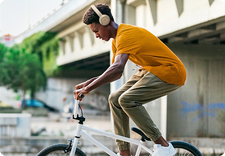 베이지 색상의 헤드폰을 착용한 남성이 자전거를 타고 있습니다.