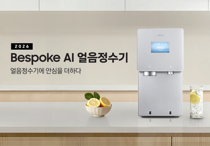 2026 Bespoke AI 얼음정수기. 얼음정수기에 안심을 더하다. 하얀색 대리석 테이블 위에 얼음정수기 사틴 베이지 컬러가 정면을 보고 설치되어 있습니다. 좌측에는 레몬이 가득 담긴 그릇이 있고 우측에는 얼음이 가득 담긴 물컵에 레몬슬라이스가 들어있습니다.