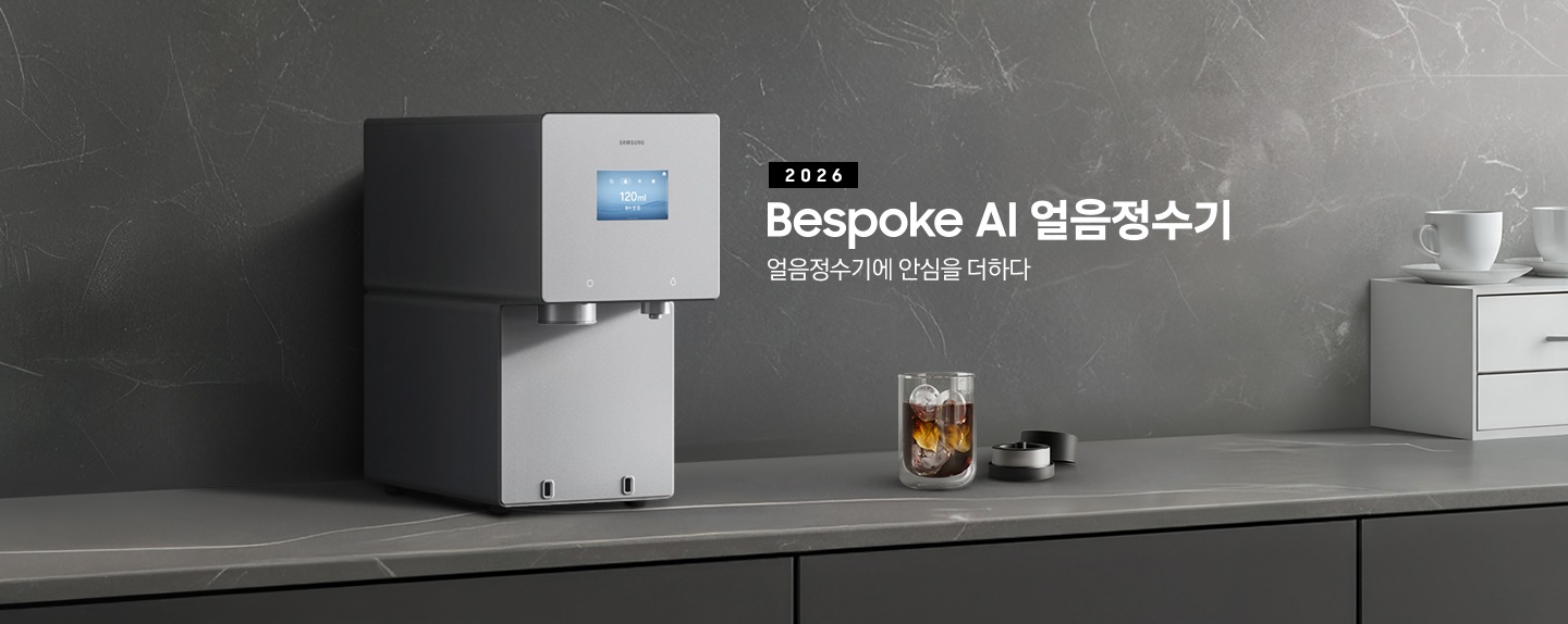 2026 Bespoke AI 얼음정수기. 얼음정수기에 안심을 더하다. 진회색 대리석 테이블 위에 얼음정수기 솝스톤 차콜 컬러가 설치되어 있는 측면 이미지 입니다. 정수기 우측에는 얼음이 가득 담긴 컵에 커피가 들어있고 옆에는 브루어 키트 뚜껑이 열려있는 이미지입니다.