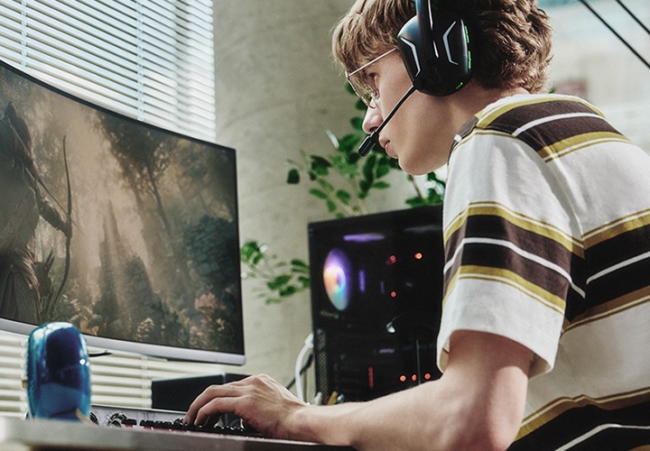 헤드셋을 끼고 PC 게임을 하고 있는 남성이 있는 이미지 입니다.