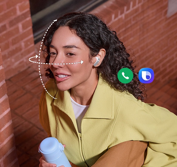 화이트 색상 갤럭시 버즈4를 착용한 사람이 한 손에는 텀블러, 다른 손에는 가방을 들고 있습니다. 얼굴을 감싸는 점선은 갤럭시 버즈4의 헤드 제스처 기능을 표현합니다. 통화 앱 아이콘과 빅스비 아이콘을 표시하여 두 기능을 헤드 제스처로 사용할 수 있음을 알려줍니다.