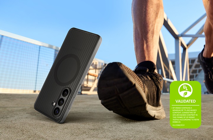 블랙 색상의 러기드 마그넷 케이스를 장착한 갤럭시 S26이 한 사람의 발걸음 옆의 지면 위로 떨어지고 있습니다. 이를 통해 케이스의 내구성과 야외 사용의 적합성을 강조하고 있습니다. '러기드 마그넷 케이스는 최소 7%의 바이오 기반 소재를 포함하고 있으며, 케이스의 프레임에는 24%의 바이오 기반 소재가 포함되어 있습니다. ASTM D6866-24에 따라 테스트되었습니다. UL.COM/ECV'라는 내용이 UL 인증 마크와 함께 표시되어 있습니다.