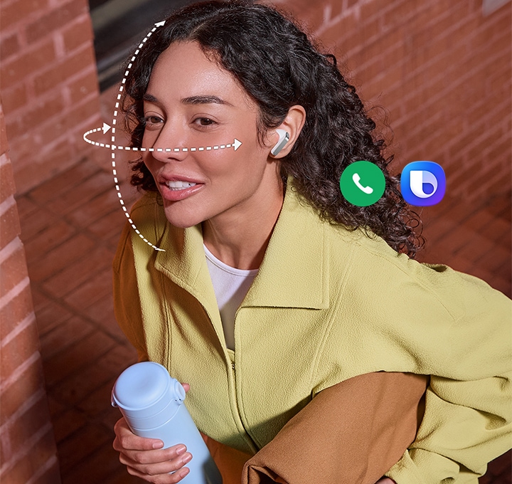 화이트 색상 갤럭시 버즈4 프로를 착용한 사람이 한 손에는 텀블러, 다른 손에는 가방을 들고 있습니다. 얼굴을 감싸는 점선은 갤럭시 버즈4 프로의 헤드 제스처 기능을 표현합니다. 통화 앱 아이콘과 빅스비 아이콘을 표시하여 두 기능을 헤드 제스처로 사용할 수 있음을 알려줍니다.