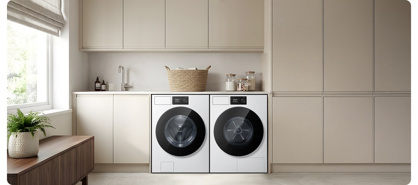 그레이톤 하부장에 세탁기와 건조기가 병렬로 설치되어 있습니다. 하부장 위에는 각종 오브제가 작은 싱크대가 설치되어 있는 연출된 이미지입니다.