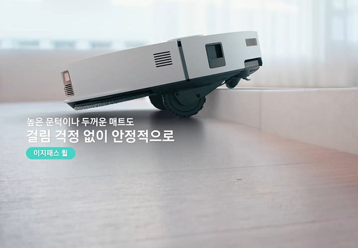 Bespoke AI 스팀 울트라가 문턱에 접근 후 전방을 스캔하여 문턱 높이가 45mm 임을 감지하고 스팀의 내부가 투영되며 5개의 바퀴가 파란색 빛으로 강조되고 있는 모습을 알려주며 제품 왼쪽 부분에는 5개 바퀴를 이용해, 계단형 60mm 단일 문턱도 최대 45mm 높이도 거뜬히 넘는 이지패스 휠 텍스트로 현재 영상 부분을 설명해 주고 있습니다. 추가로 영상의 하단 부분에는 단일 문턱 기준 최대 45mm/ 계단형 단차 기준 하부 45mm 및 추가 15mm 층을 포함한 60mm를 통과할 수 있으며, 각 층 사이의 간격이 90mm 이상이어야 하는 부분을 그림으로 그려 설명하고 있습니다. 이어서 전방 휠 하강으로 몸체를 들어 올리고 이지패스 휠 텍스트가 왼쪽에 쓰여 있으며, Bespoke AI 스팀 울트라의 바닥 부분을 보여주며 5개 바퀴 중 제일 앞부분에 있는 전방 휠이 하강하면서 몸체를 들어 올리는 모습을 알려주고 있습니다. 다음 장면은 메인&사이드 휠 하강으로 문턱 위 이동 및 충격 방지 이지패스 휠 텍스트가 왼쪽에 쓰여 있고 메인 휠과 사이드 휠이 하강한 후 Bespoke AI 스팀 울트라가 자동으로 문턱/ 두꺼운 매트를 넘는 모습을 설명해주는 영상입니다. 계속 이어서 높은 문턱이나 두꺼운 매트도 걸림 걱정 없이 안정적으로 라는 텍스트가 왼쪽에 쓰여 있으며 Bespoke AI 스팀 울트라가 높은 곳을  자동으로 높이가 조절되며 본체를 들어올려 두꺼운 매트를 올라 그 위를 돌아다니는 Bespoke AI 스팀 울트라의 상단 모습과 집 안 곳곳을 어디든 자유롭게 텍스트가 나타나며 영상이 마무리 됩니다.