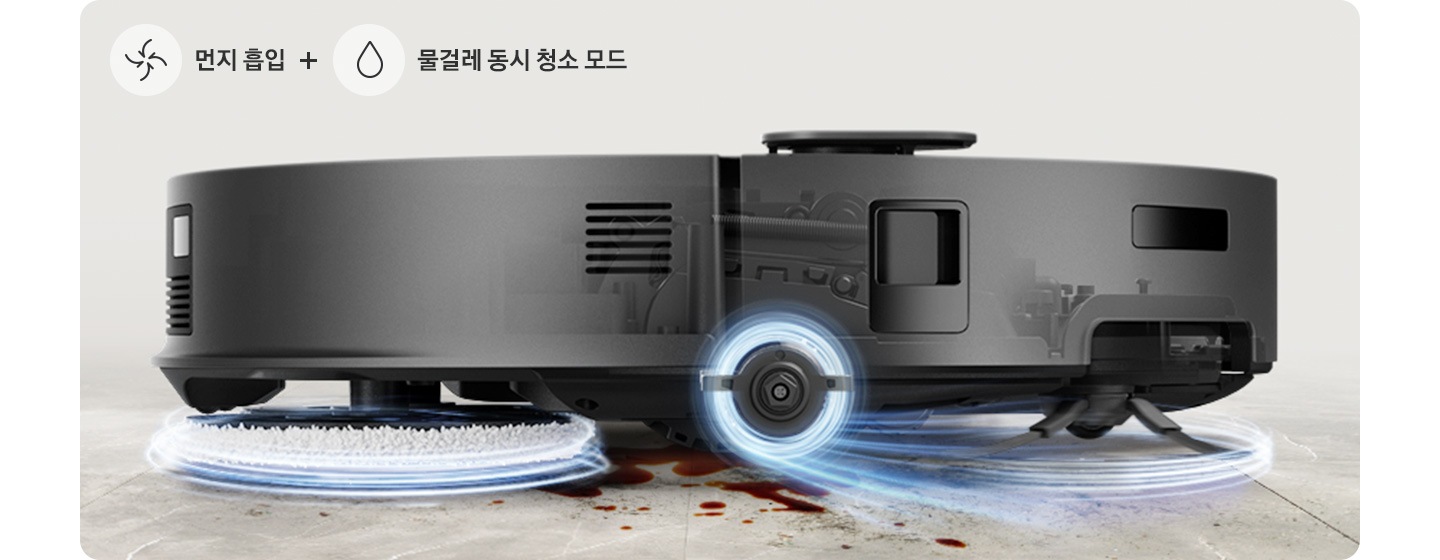 브라운 색상과 연한 회색이 섞인 대리석 바닥에 Bespoke AI 스팀 플러스의 옆모습이 놓여있고 각각 뒷부분의 물걸레와 앞부분의 브러시가 동시에 청소하고 있는 이미지입니다. 물걸레와 브러시가 각각 푸른빛으로 된 선으로 감싸져 있어 돌아가고 있는 모습을 표현하고 있으며, 이미지 왼쪽 하단 부분에는 중간으로 빨려 들어가는 화살표와 물방울 아이콘이 중간에 +를 두고 나열되어 있고 아이콘 오른쪽 부분에는 먼지 흡입 + 물걸레 동시 청소 모드 텍스트가 쓰여있습니다.