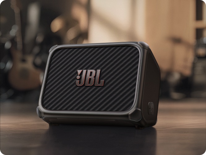 BANDBOX TRIO가 바닥에 놓여 있으며, 그 뒤로는 기타와 드럼 등 악기들이 흐릿하게 처리되어 있습니다.