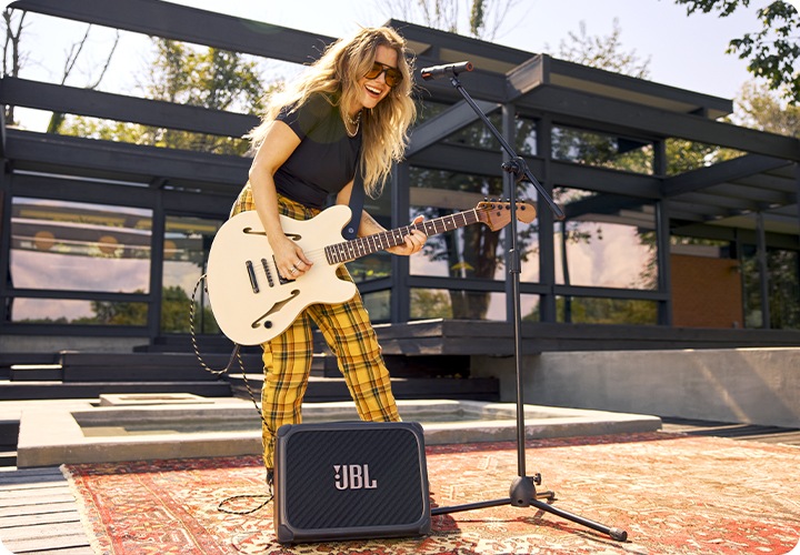 BANDBOX TRIO에 기타를 연결한 여성이 길거리에서 연주하고 있습니다.